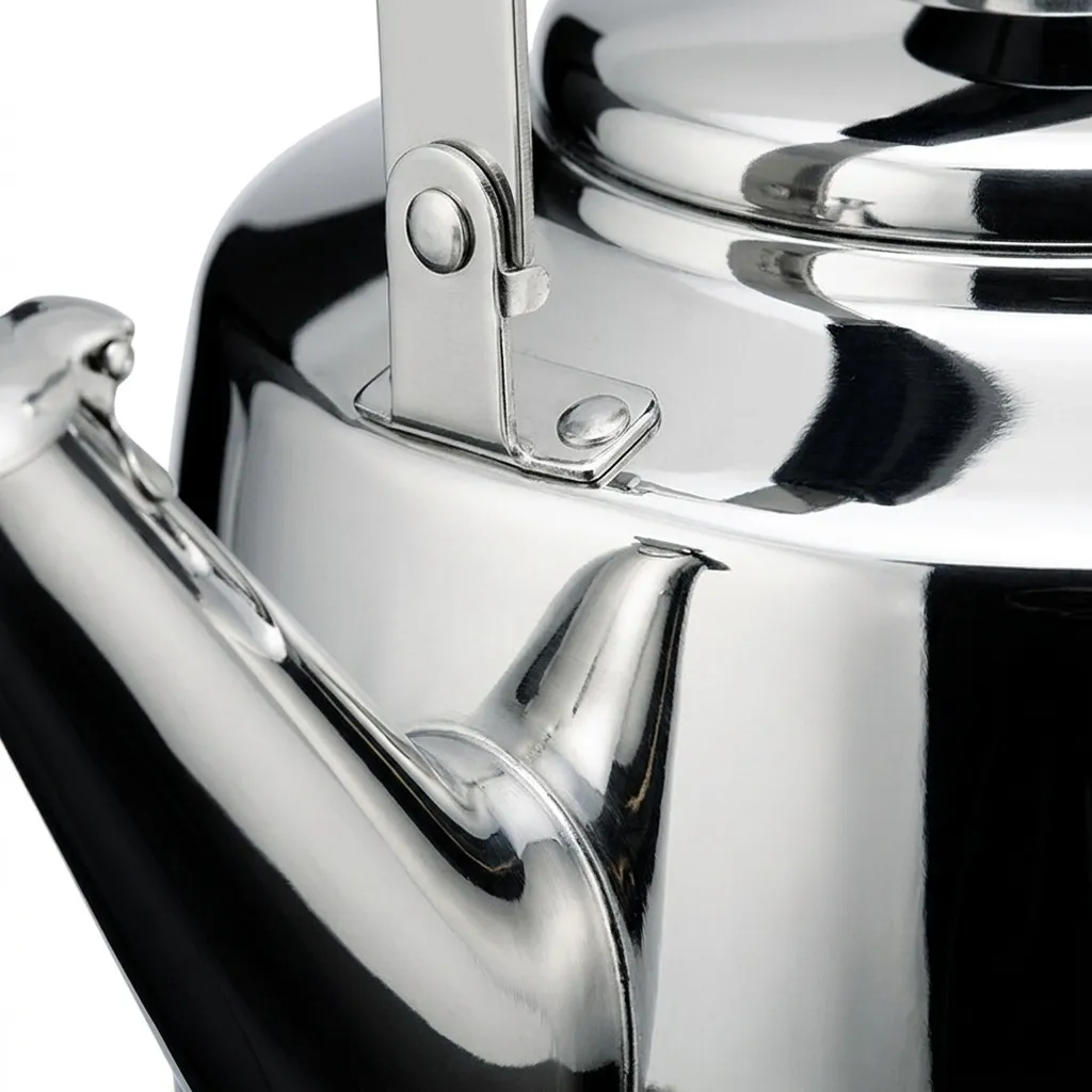 Close-up of the mirror-polished kettle where the spout meets the body, with the riveted handle bracket above it