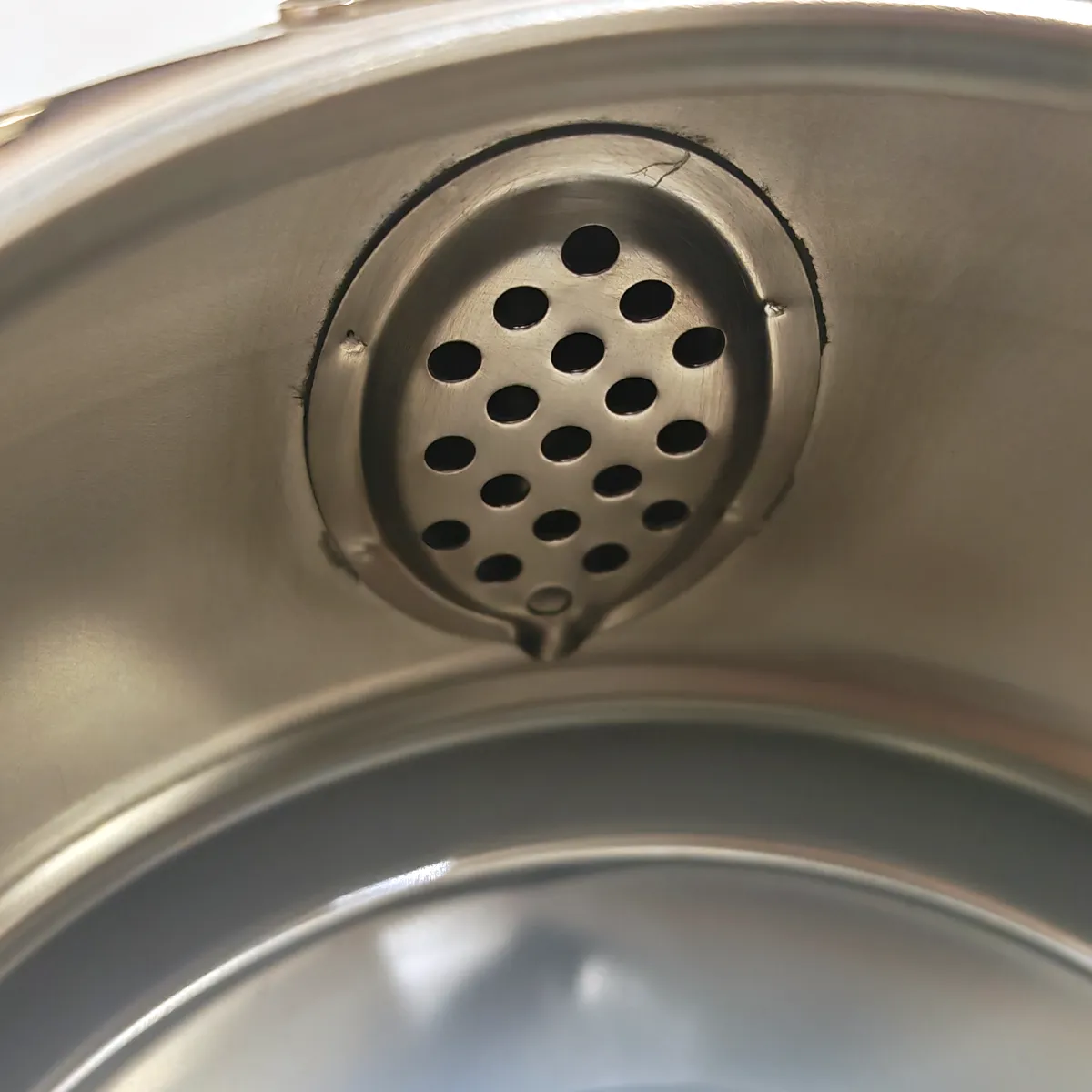 Interior of the kettle showing the perforated strainer seated in a recess over the spout opening